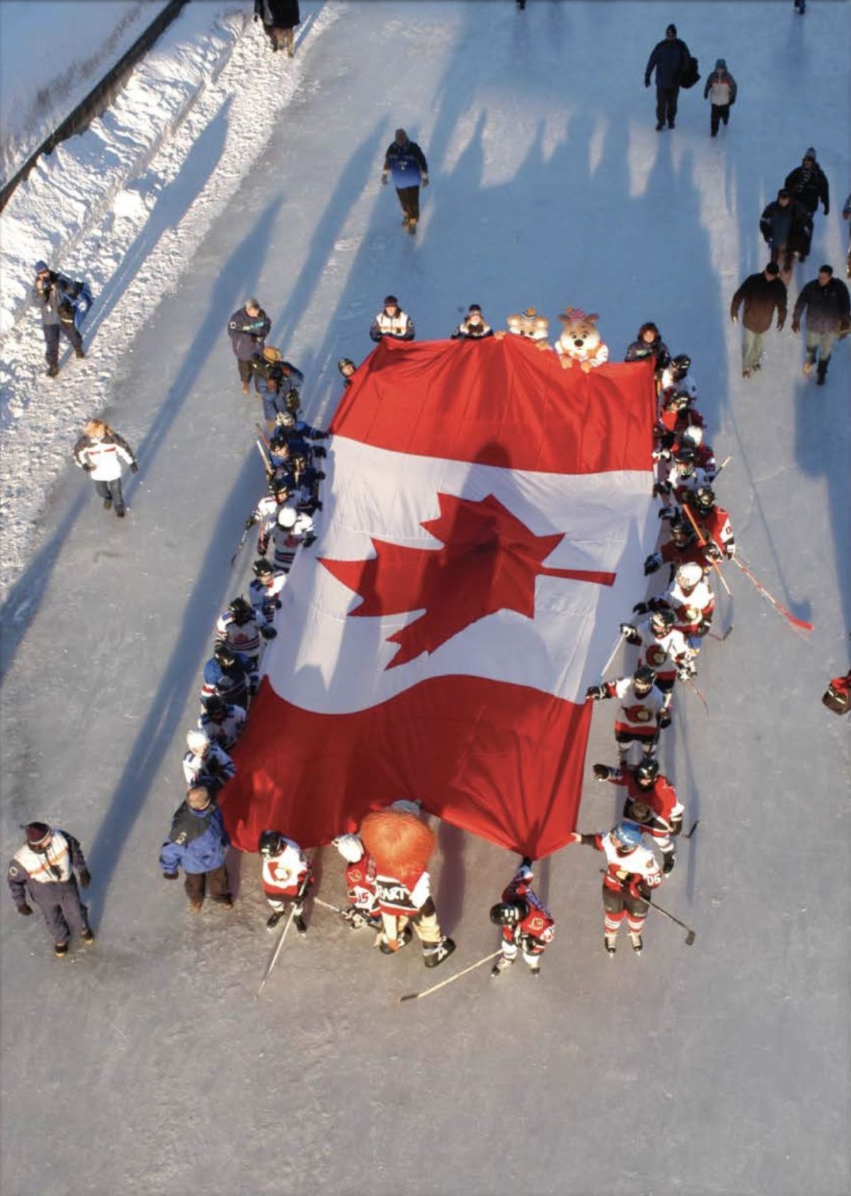 Des gens qui tiennent le drapeau du Canada sur la patinoire du canal rideau.